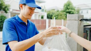 Asia postal delivery courier man in blue shirt handling food boxes for sending to customer